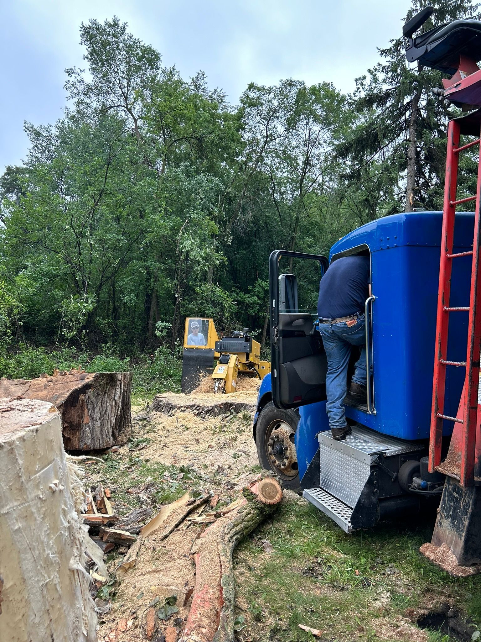 A man is standing on the back of a blue truck.