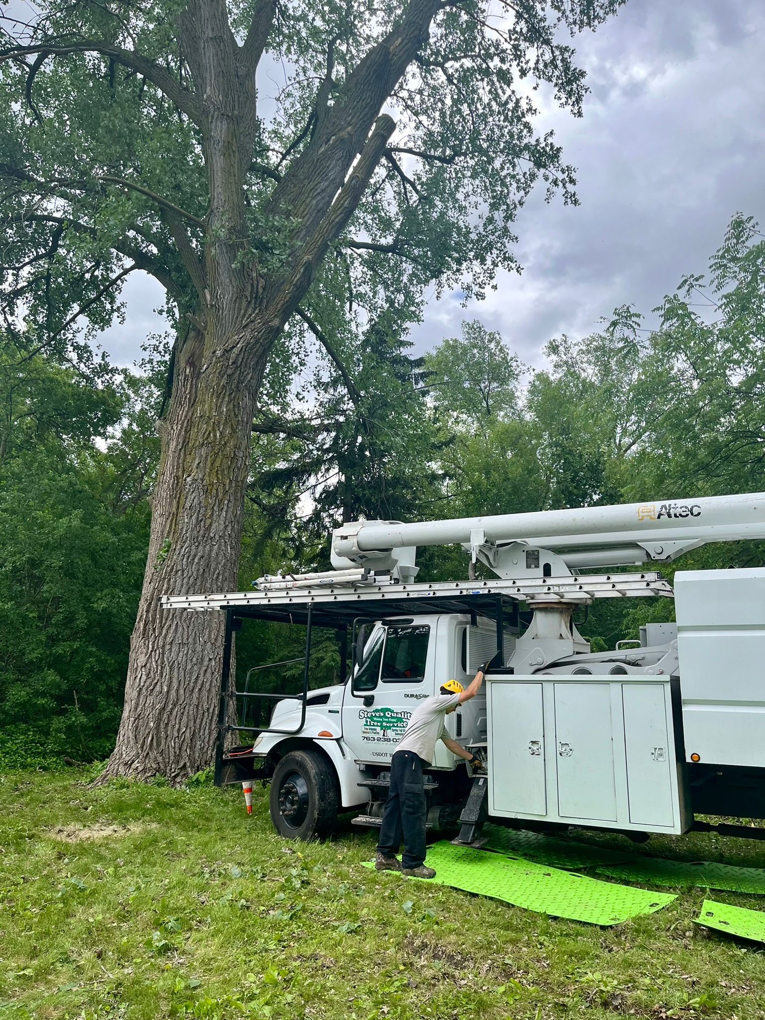 A man is standing next to a white truck with a crane attached to it.