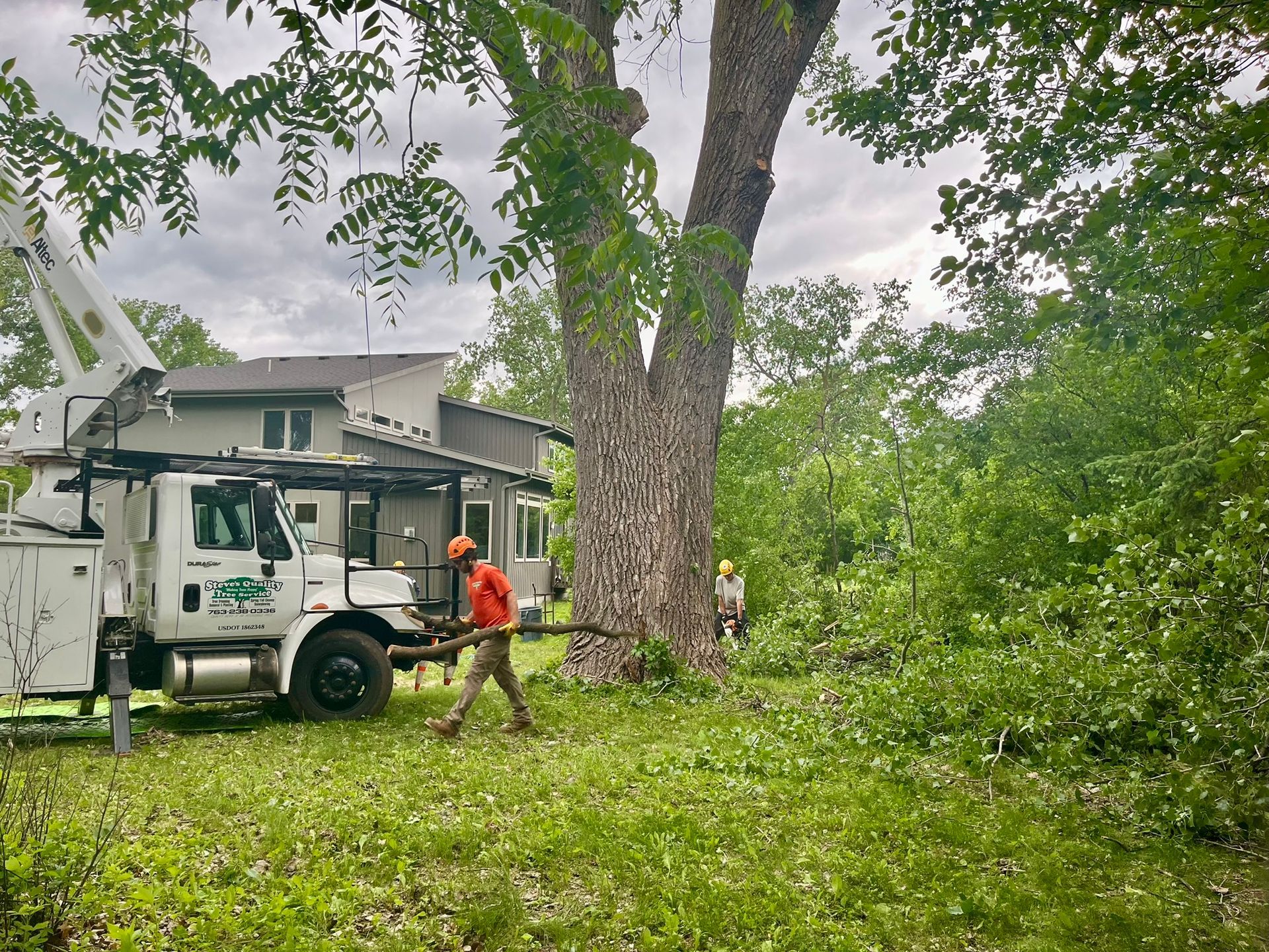 A man is walking in front of a tree trimming truck.