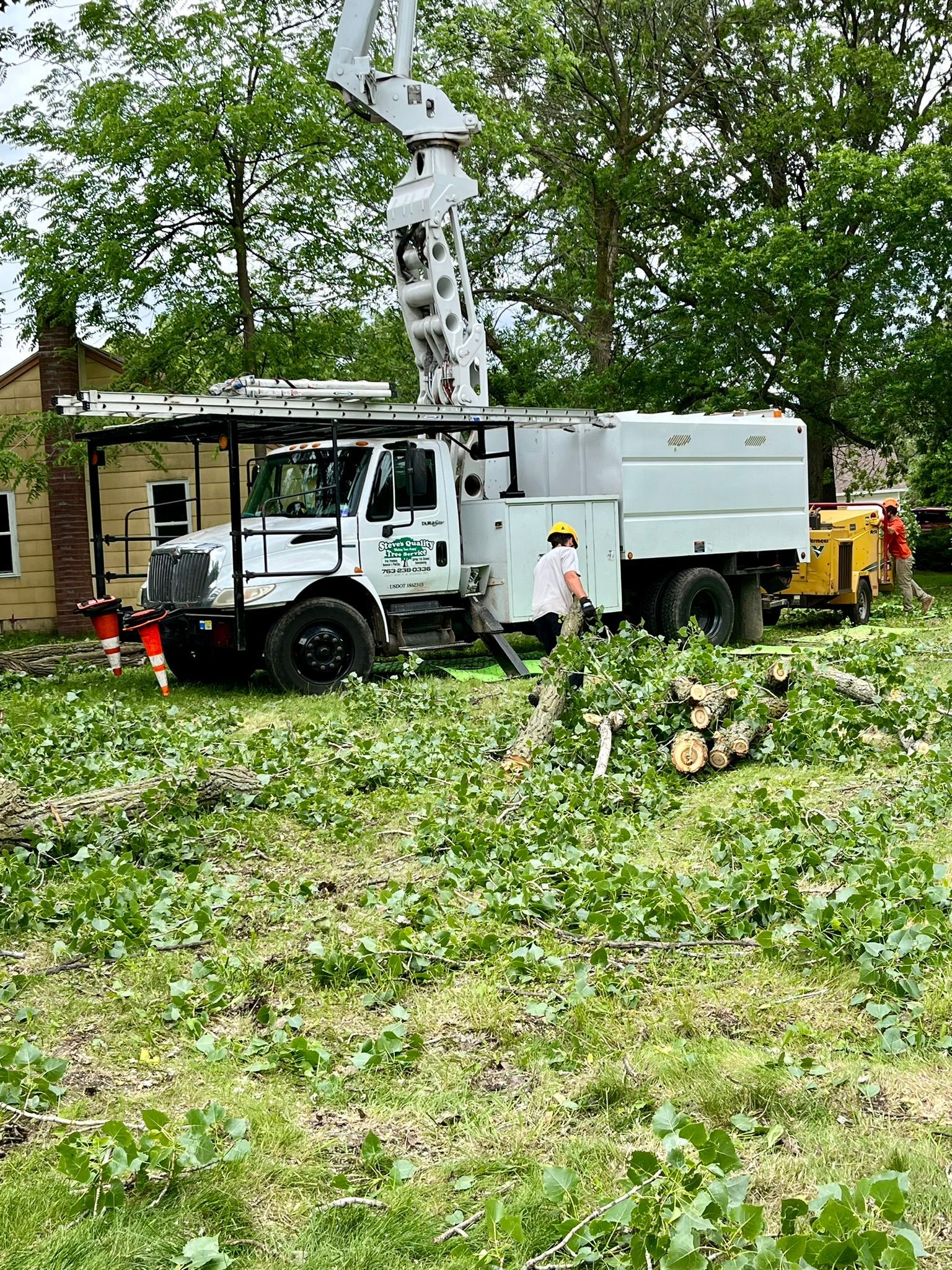 A white truck is parked in a grassy field next to a house.