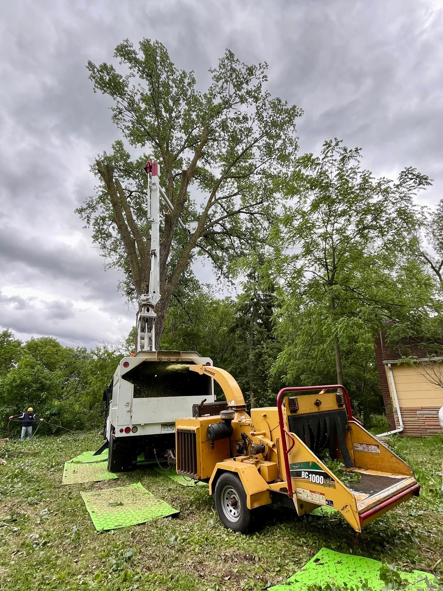 A tree chipper is sitting next to a truck in a field.