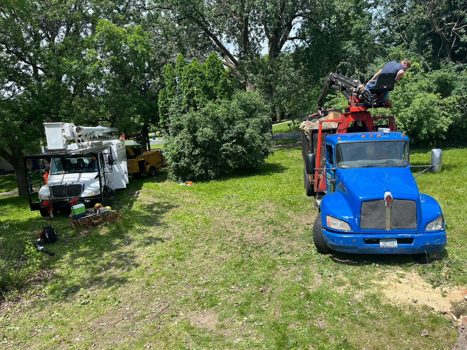 A blue truck is parked in a grassy field next to a white truck.