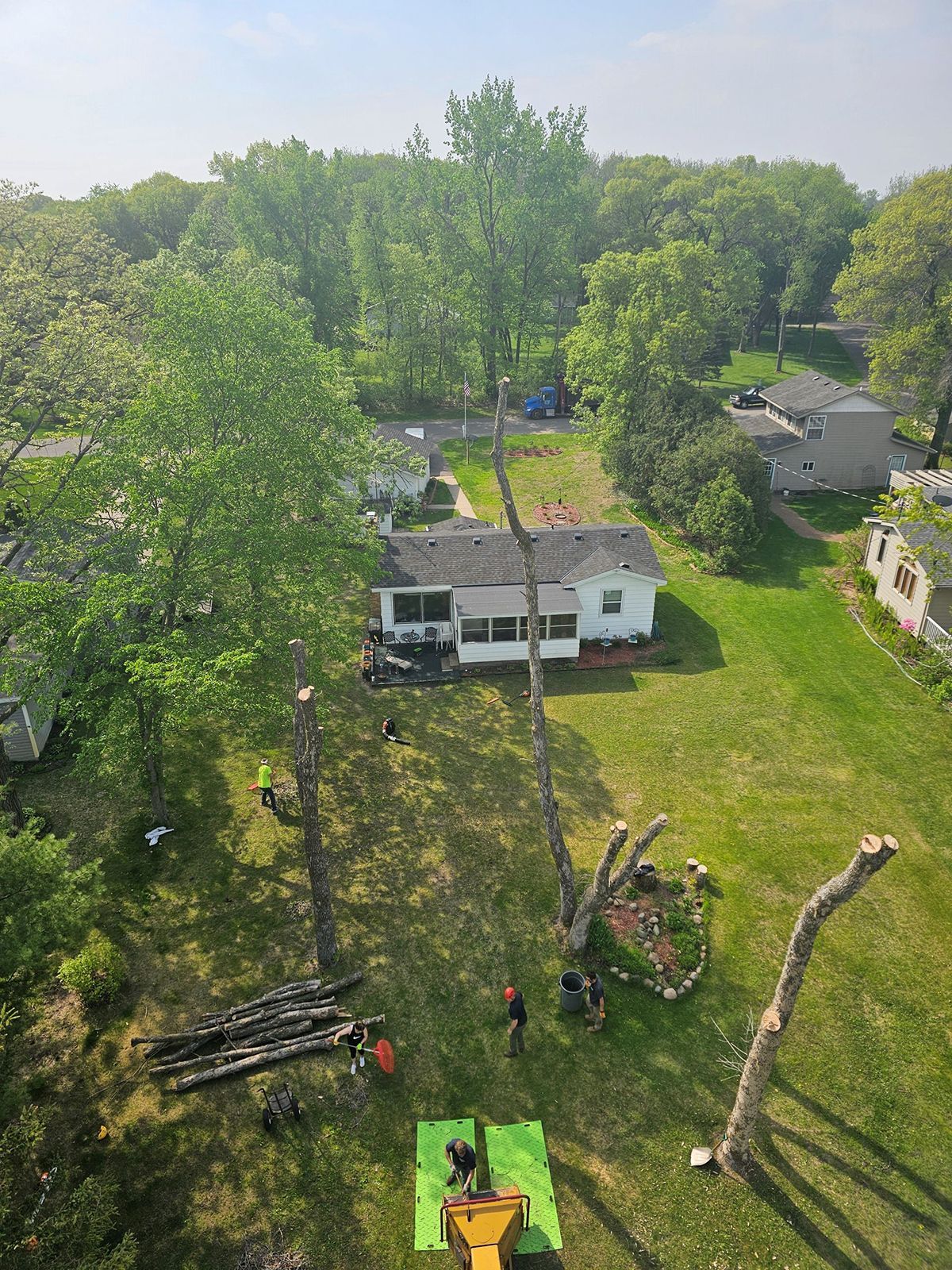 An aerial view of a tree being cut down in front of a house.