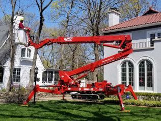 A red crane is sitting in front of a house.