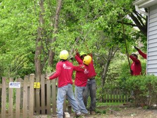 A group of men are working on a fence in front of a house.