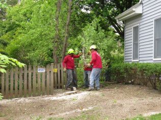 A group of men are working on a fence in front of a house.