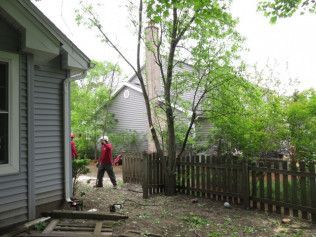A man is standing in front of a house next to a fence.