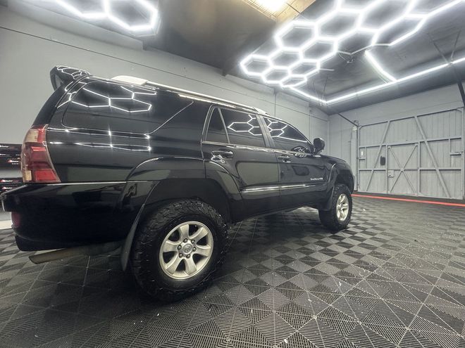 Black Toyota 4Runner SUV inside a garage with patterned flooring and honeycomb ceiling lights.