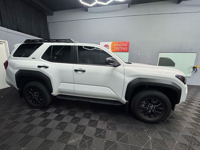 White SUV with black accents, parked in a garage with tinted windows and black rims.