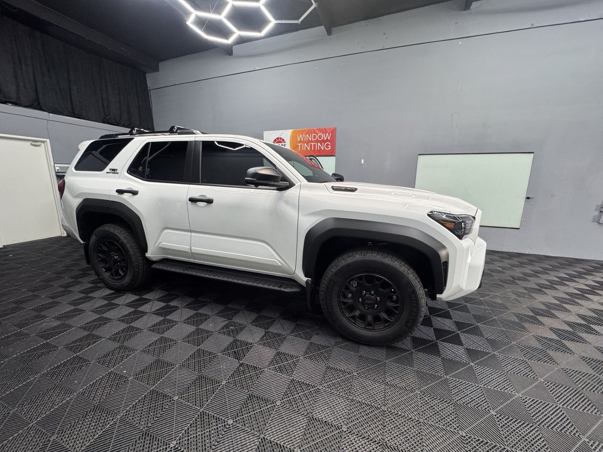 Dark gray Dodge Challenger parked in front of a window tinting business.