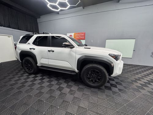 Dark gray Dodge Challenger parked in front of a window tinting business.