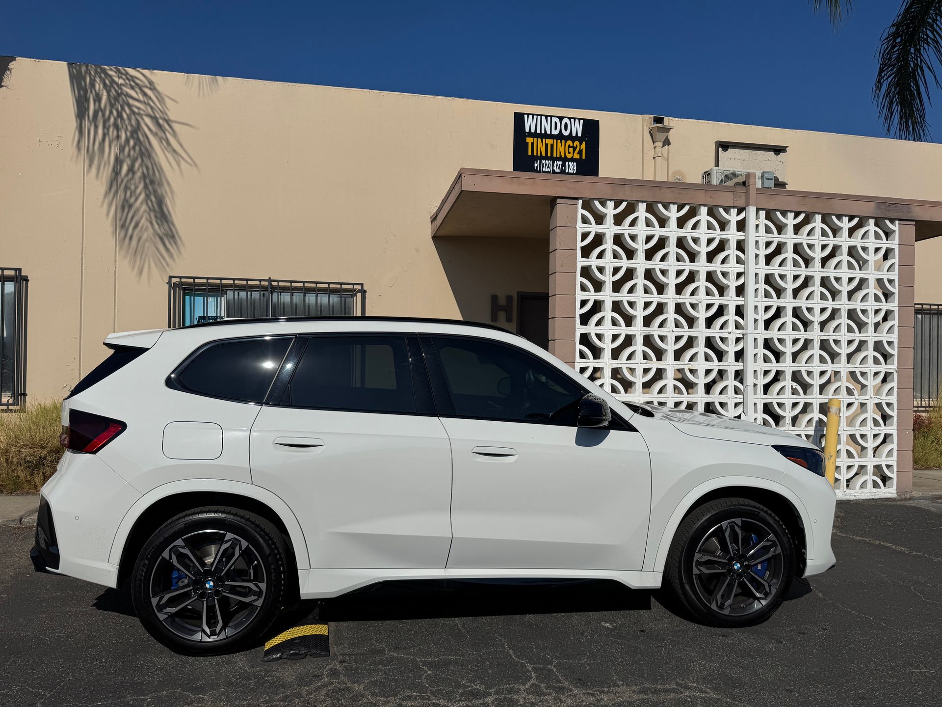White SUV parked in front of a building with a sign that reads