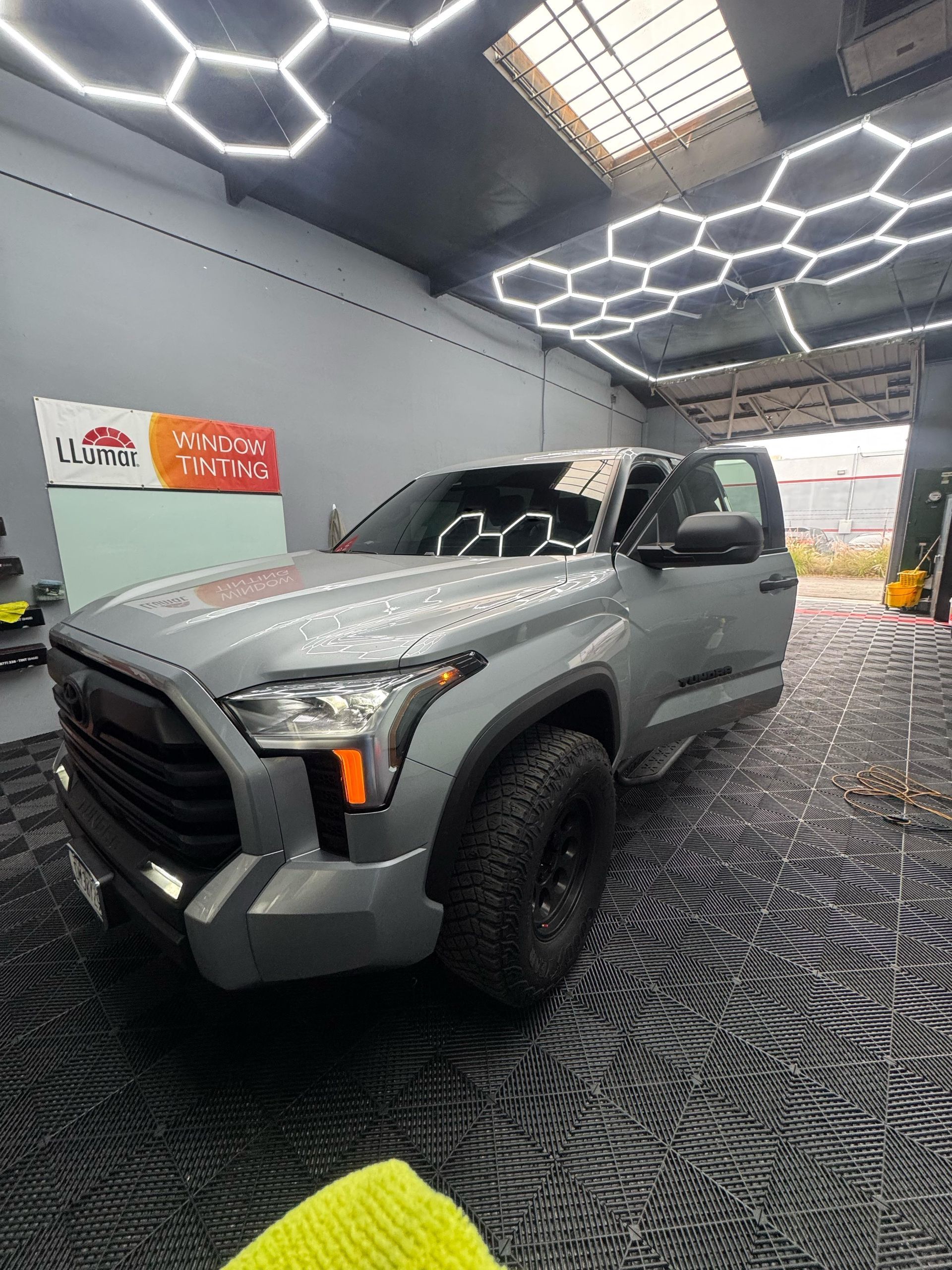 Gray Toyota pickup truck inside a shop with hexagonal lights and open door.