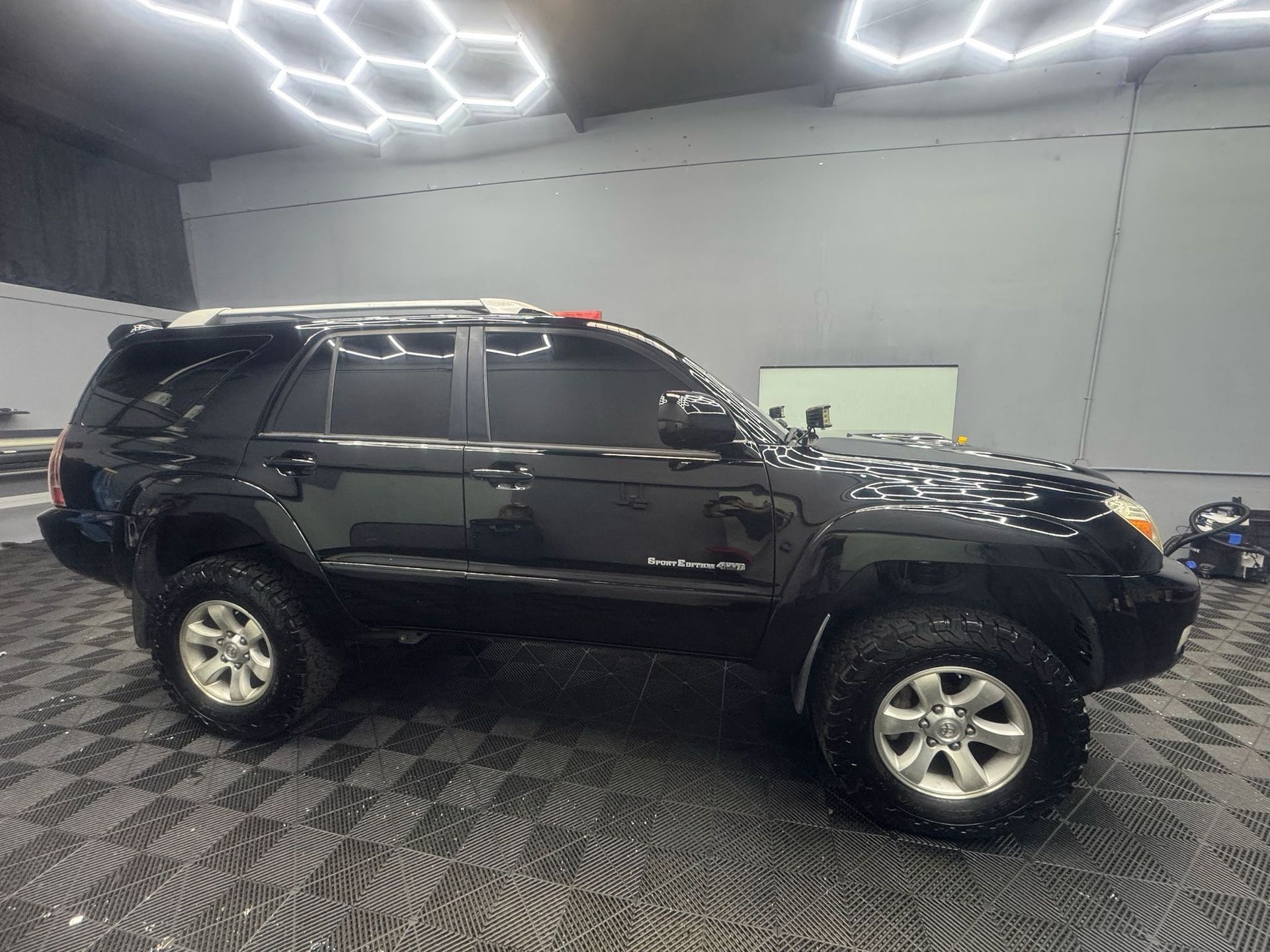Black SUV parked inside a garage, with tinted windows and off-road tires.