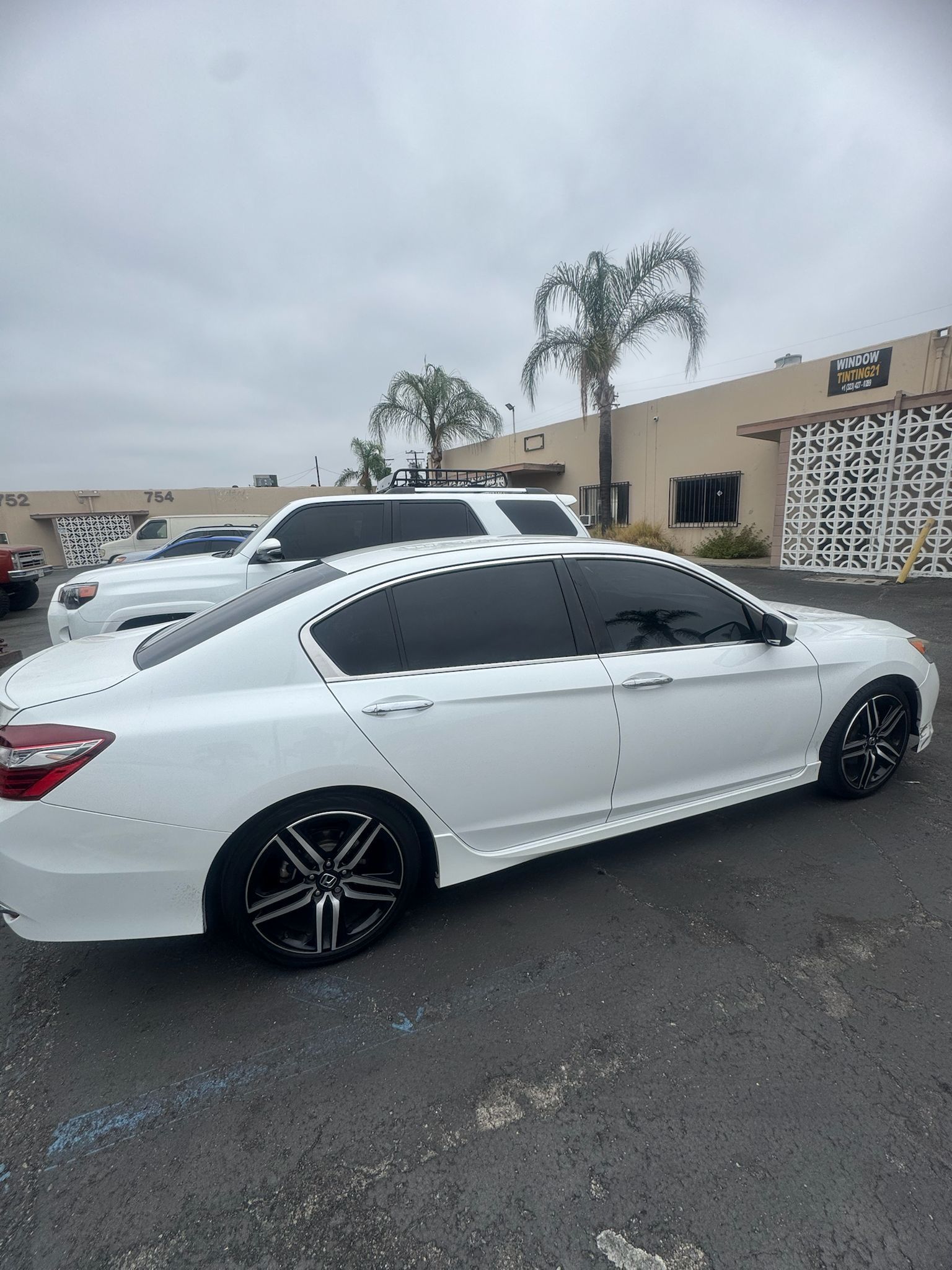 White sedan with tinted windows and black rims parked on asphalt.