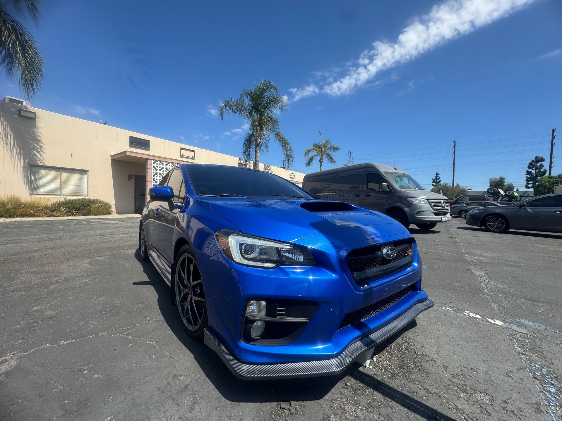 Blue Subaru WRX parked outside a building on a sunny day.
