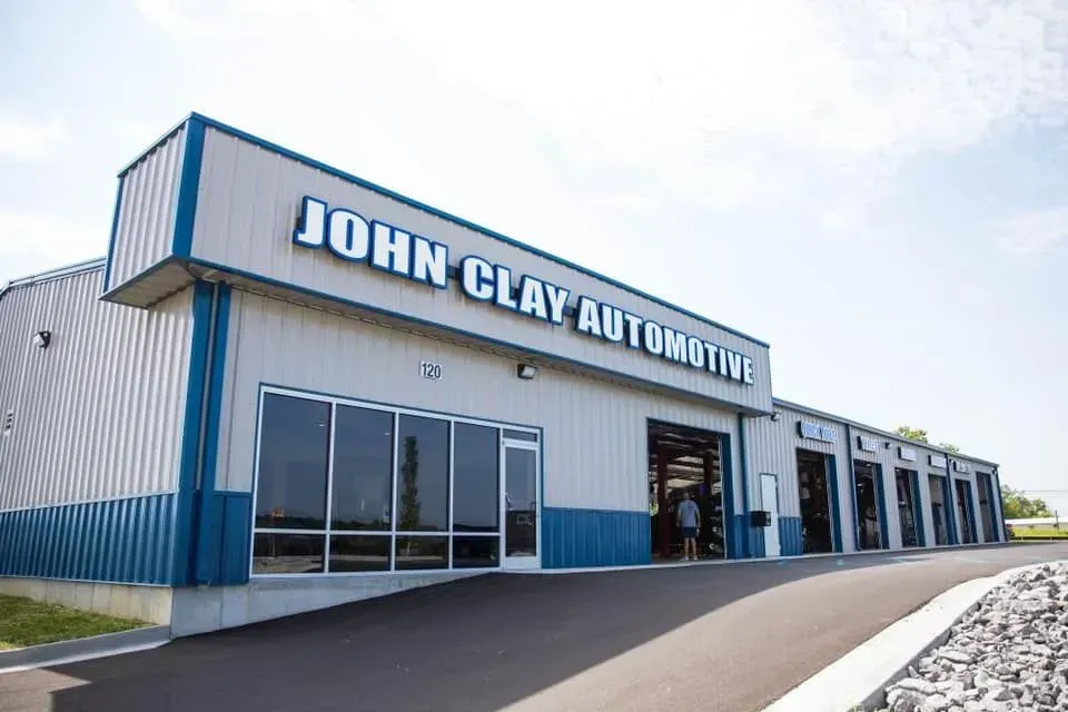 John Clay Automotive building exterior with blue and gray facade, multiple bays, and sign.