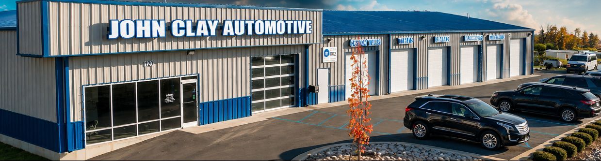 John Clay Automotive with blue-striped building, glass entrance, and parked cars in front