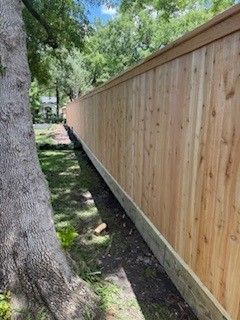 A wooden fence is sitting next to a tree in a yard.