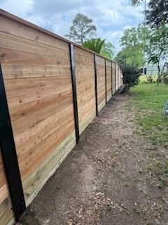 A wooden fence is sitting on top of a dirt path in a backyard.