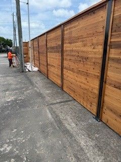 A wooden fence is being built on the side of a road.
