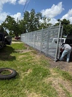 A man is working on a fence in a yard.