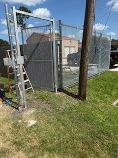 A chain link fence with a gate is being built in a yard.