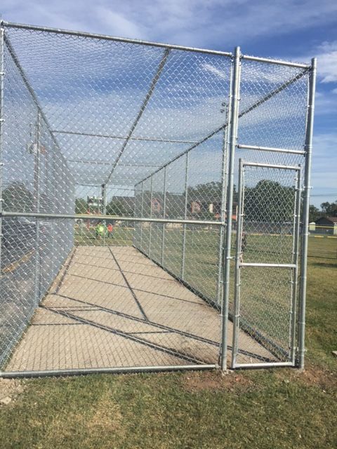 A chain link fence is surrounding a baseball field.