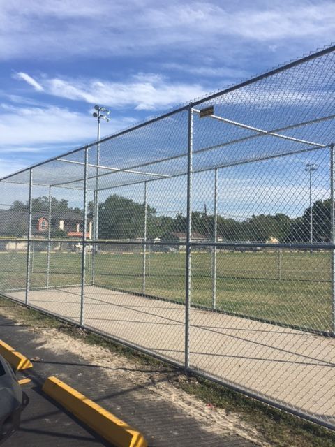 A chain link fence surrounds a baseball field on a sunny day