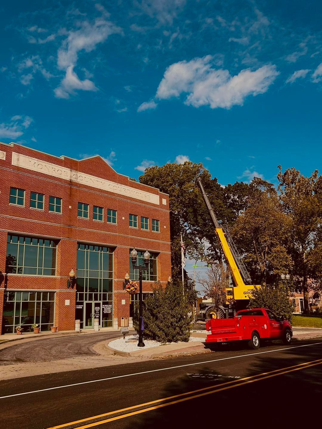 A crane parked in front of a large brick building