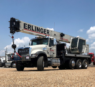 A truck with a crane on top of it is parked in a gravel lot