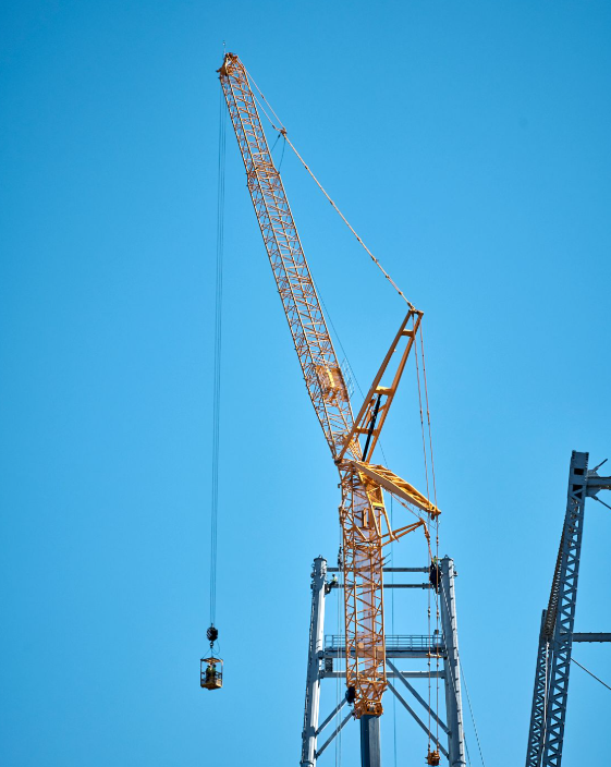 a construction crane is being used to lift a bucket against a blue sky