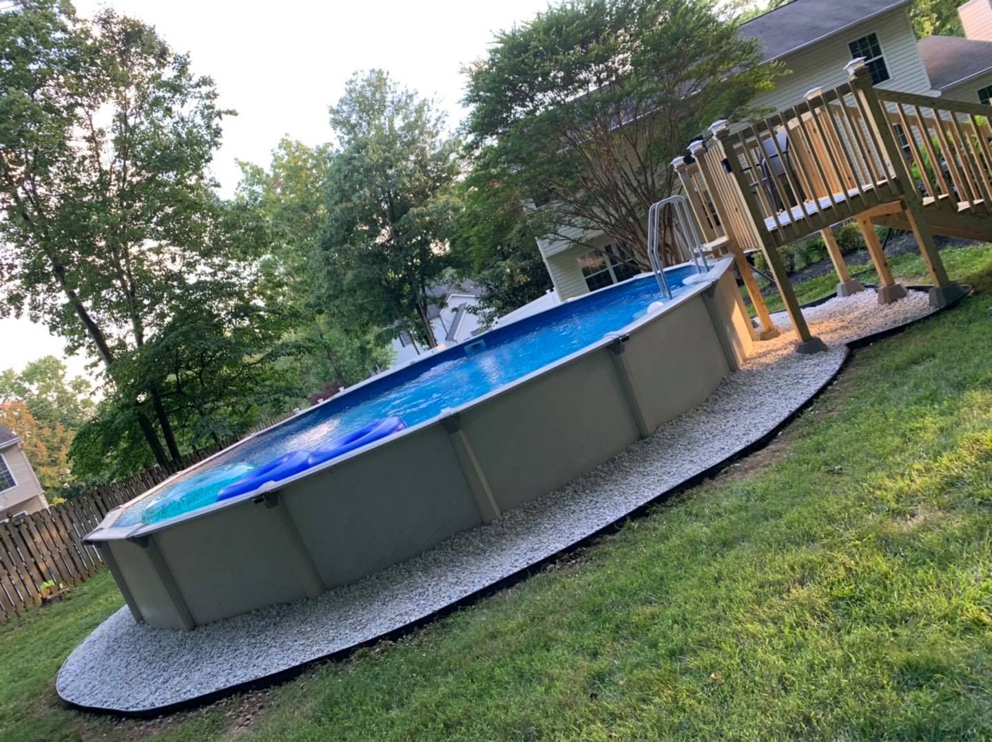 Above-ground pool in a backyard with a wooden deck and trees.