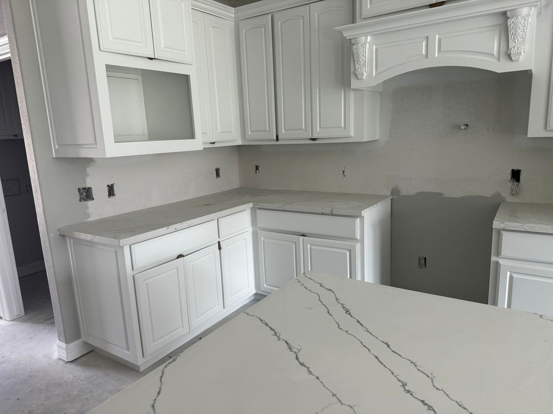 A kitchen with white cabinets and a white counter top.
