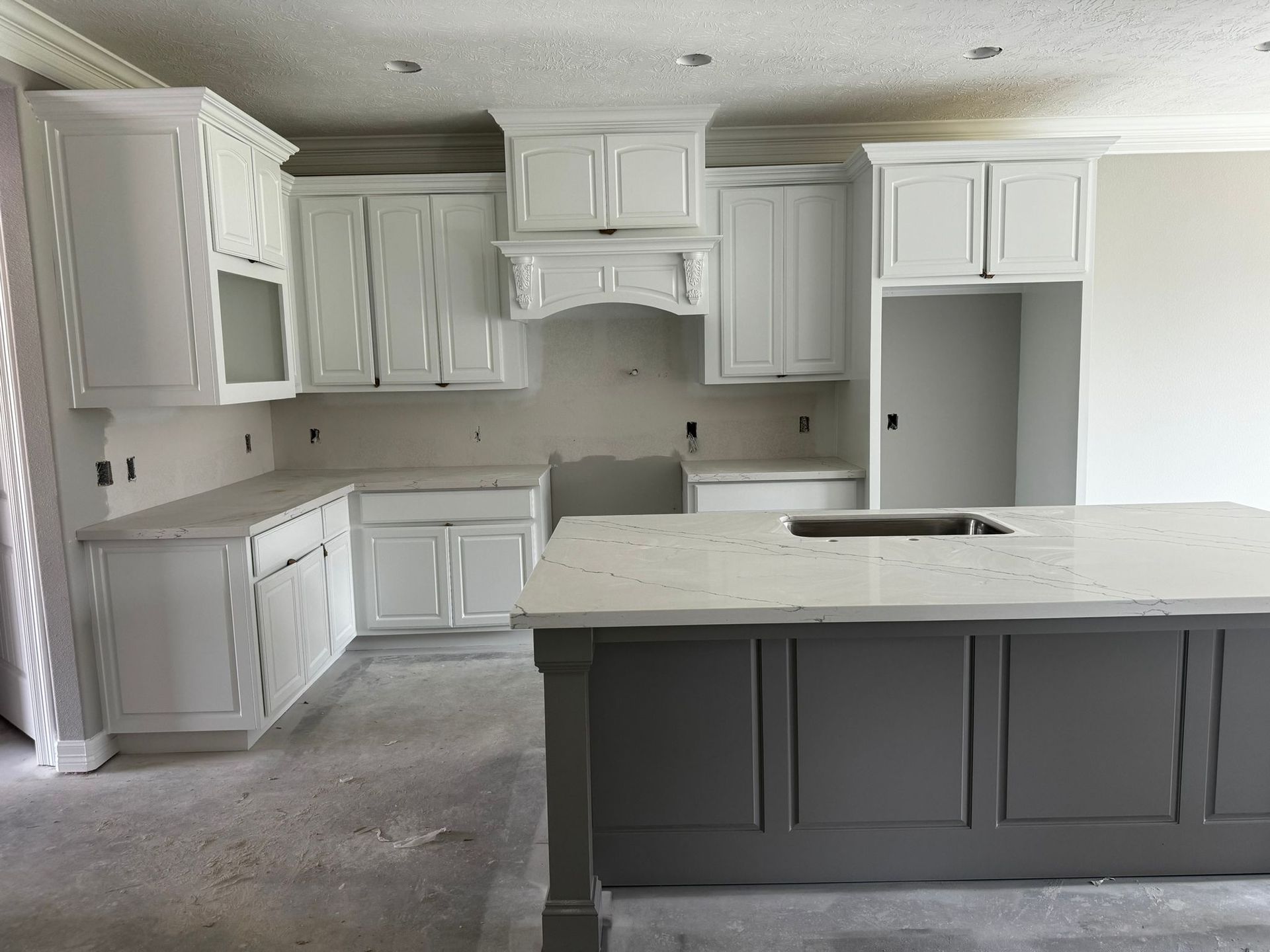 A kitchen with white cabinets and a gray island