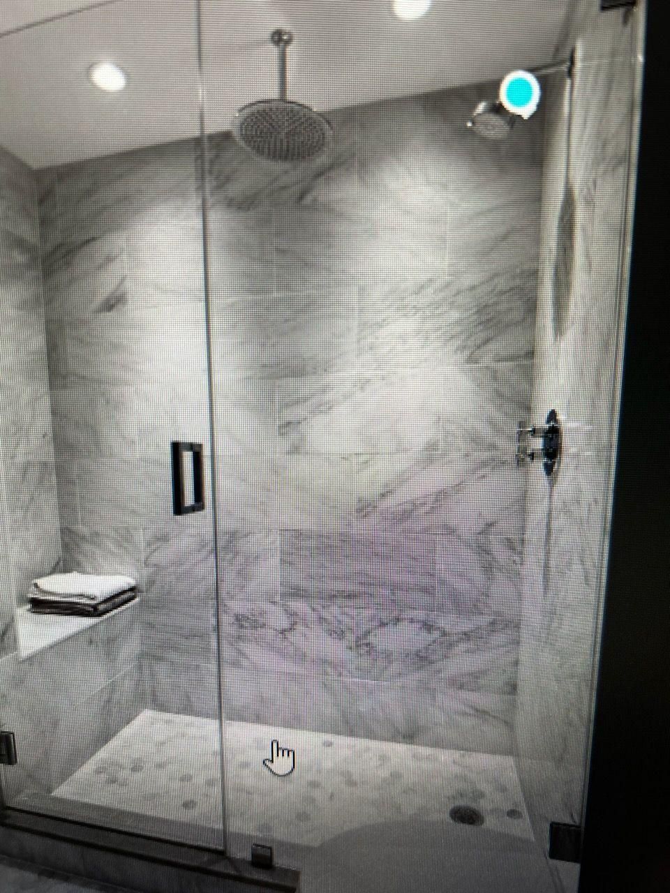 A bathroom with a walk in shower with a glass door and a shower head.