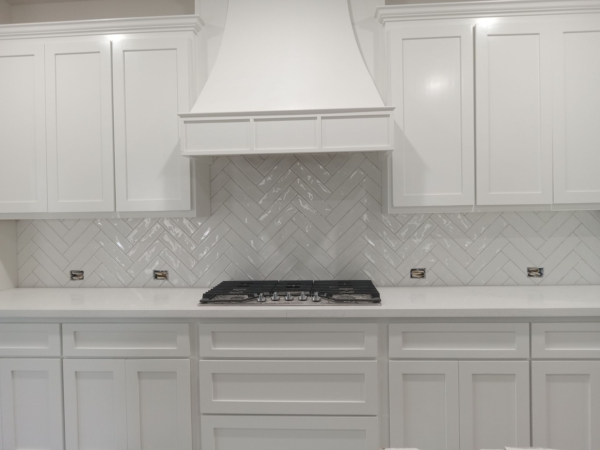 A kitchen with white cabinets and a stove top oven.