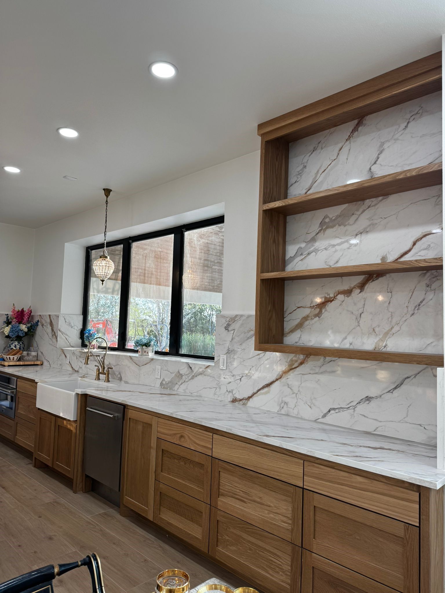 A kitchen with marble counter tops , wooden cabinets , a sink and a window.