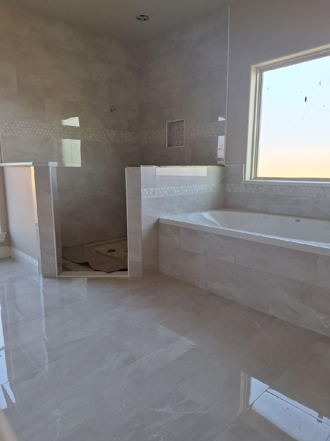 A bathroom with a tub , shower , and window.