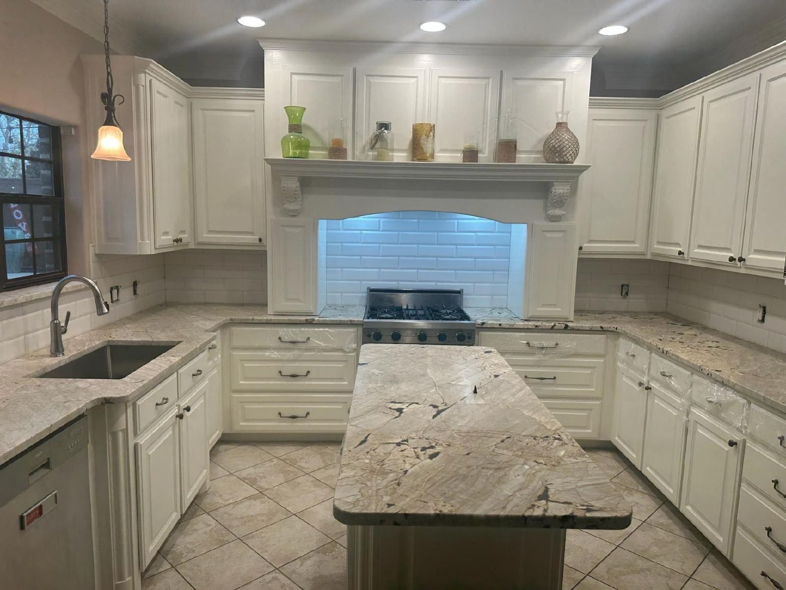 A kitchen with white cabinets , granite counter tops , and a large island.