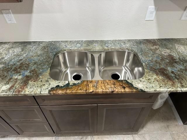 A kitchen sink is sitting on top of a granite counter top.
