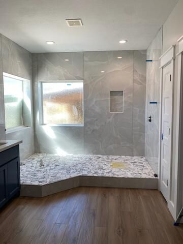 A bathroom with a walk in shower and a window.