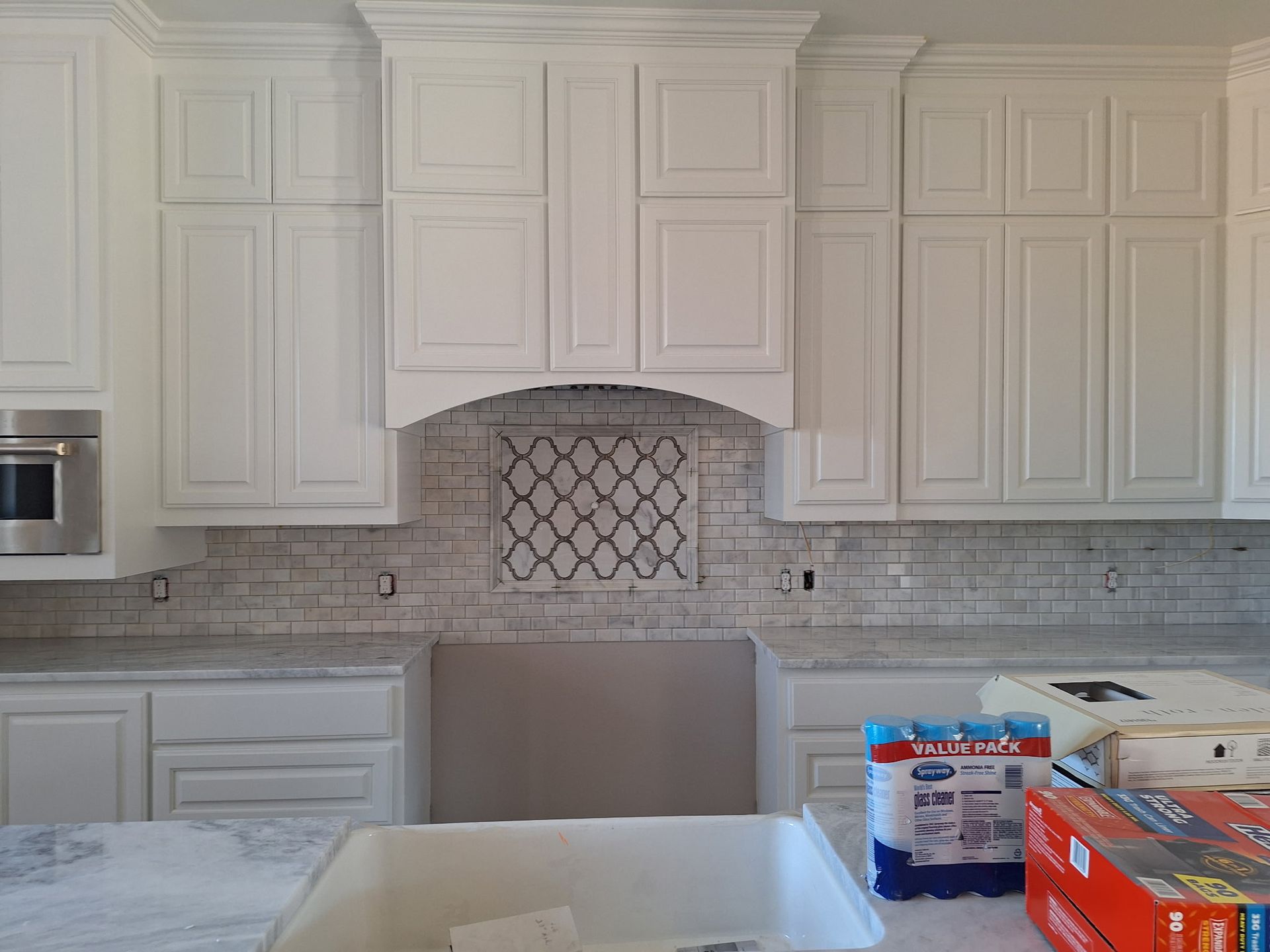 A kitchen with white cabinets , a sink , and a stove.