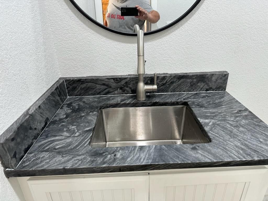 A person is taking a picture of a sink in a bathroom.