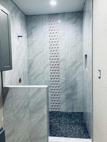 A bathroom with a walk in shower and a tiled wall.
