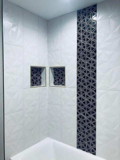 A bathroom with white tiles and a black tile on the wall.