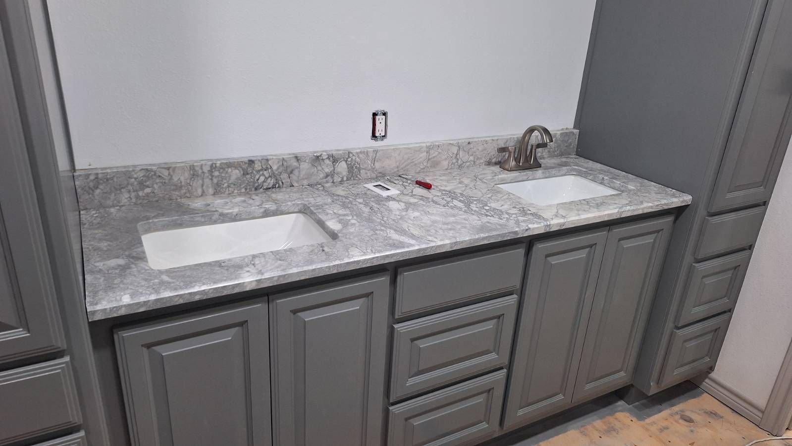 A bathroom with two sinks and gray cabinets.