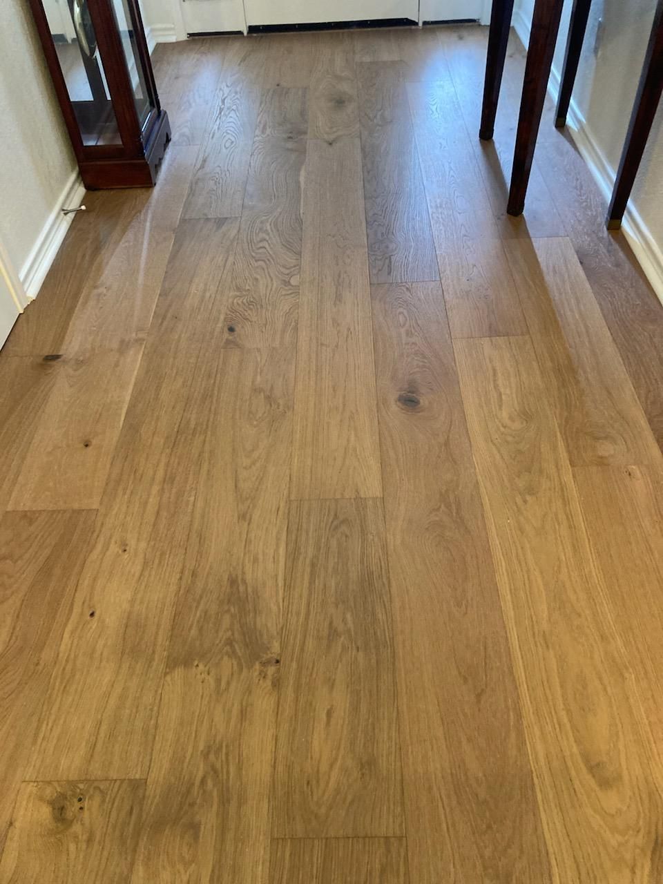 A wooden floor in a room with a table and a mirror.