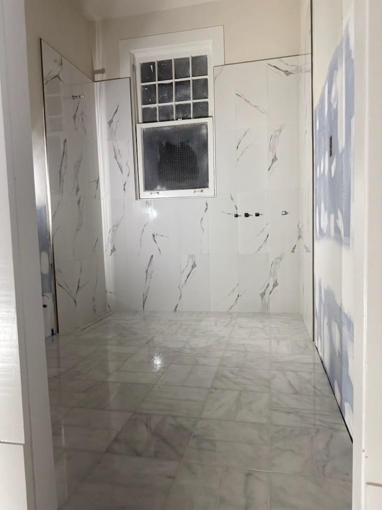 A bathroom with white tiles and a window.