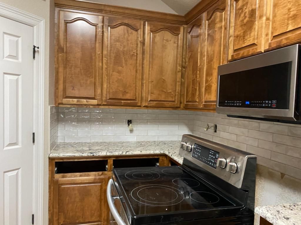 A kitchen with wooden cabinets , a stove , and a microwave.